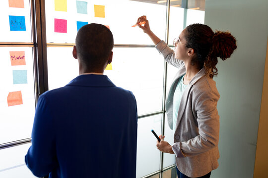 Multiracial businesswomen planning business strategy over colorful sticky notes in creative office