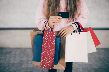 Young happy woman holding paper bags and boxes and credit card.