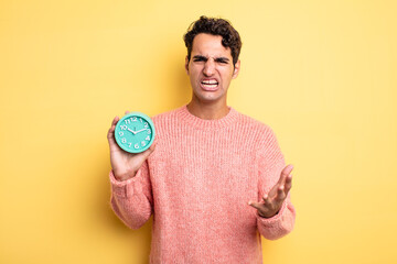 young handsome man looking angry, annoyed and frustrated. alarm clock concept