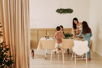 Christmas concept. Children help their mother to set the table. A large family with one parent is preparing for the Christmas holiday in a decorated room during the New Year holidays. Selective focus