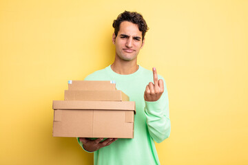 young handsome man feeling angry, annoyed, rebellious and aggressive. package boxes
