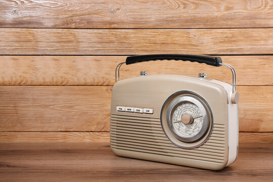 Retro radio receiver on table against wooden background. Space for text