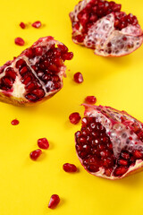 Vertical image of bright juicy pomegranate,seeds on the colorful yellow background.Mockup for pomegranate drinks