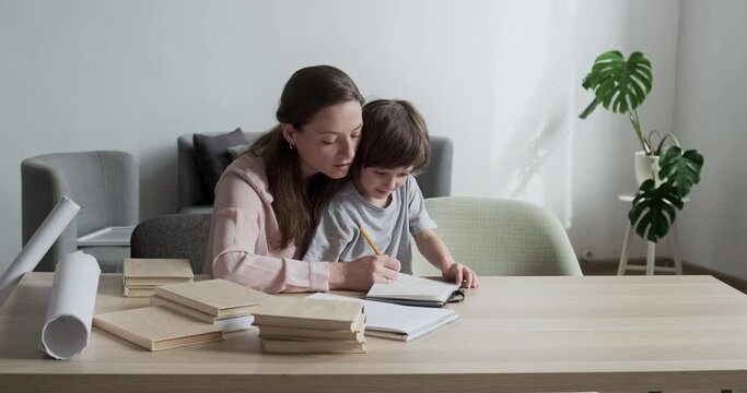 Beautiful single mother studying and teaching child how to count and write at home. In homeschooling, logic and math abilities taught simultaneously. A youngster boy educated by female instructor.