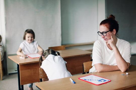 Crazy woman teacher at a desk with a girl student. Unusual photos of schooling, learning difficulties. Conflicts and misunderstandings between student and teacher,