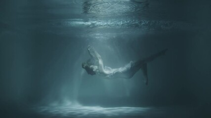 a girl in a white dress falls under the water