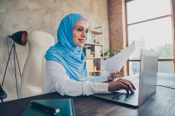 Photo of friendly young ceo arabian lady write paper laptop wear eyewear scarf shirt indoors workplace