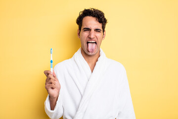 young handsome man with cheerful and rebellious attitude, joking and sticking tongue out. bathrobe...