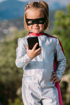 Brave girl in superhero costume browsing on smartphone