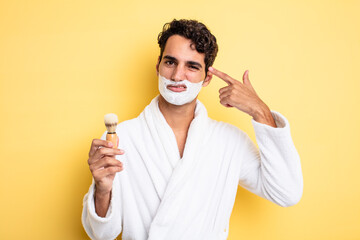 young handsome man feeling confused and puzzled, showing you are insane. shaving and foam concept