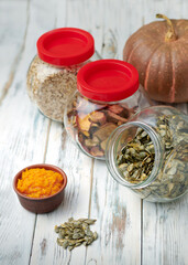 Dry pumpkin seeds in a glass jar on a white wooden board