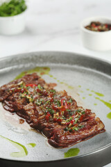 grilled beef chuck steak closeup. sliced steak with chili pepper on ceramic plate