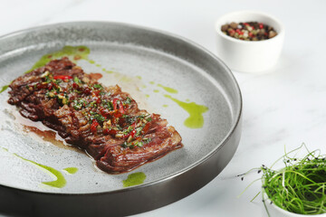 grilled beef chuck steak closeup. sliced steak with chili pepper on ceramic plate