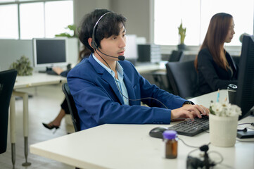 Asian Operators are wearing headphone working in workplace .