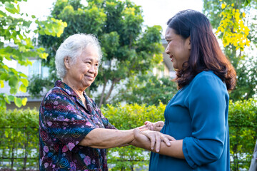 Asian elderly woman with caregiver walking with happy in nature park.