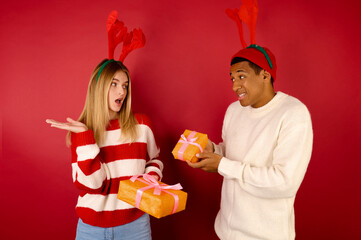 A young coupe in reindeer hats holding gift boxes
