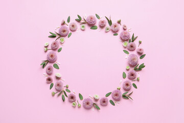 Wreath made of beautiful flowers and green leaves on pink background, flat lay. Space for text