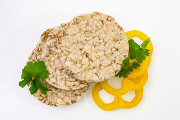 Round crispy popcorn and rice bread with yellow bell pepper rings and spicy herbs. Isolated on a...