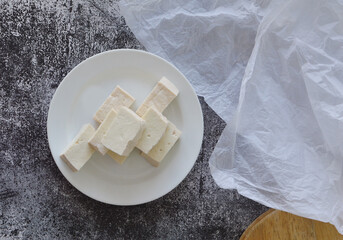A plate of fresh tofu cubes on ceramic plate in rustic background
