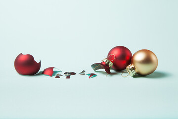 Broken red christmas ball and safe two christmas ball on light blue background