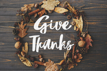 Give thanks text on autumn wreath flat lay on dark rustic wood. Happy thanksgiving Seasonal...
