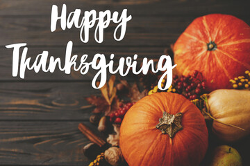 Happy thanksgiving text on pumpkins, autumn leaves, anise, berries, acorns border on rustic wood. Seasonal greeting card, handwritten sign. Give thanks