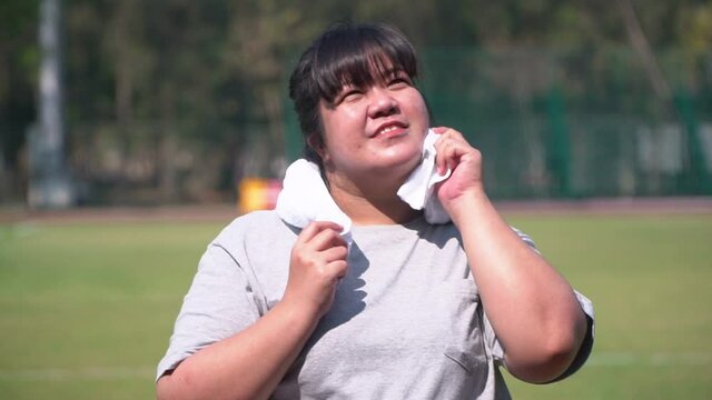 Happy overweight Asian women Use a towel to wipe away sweat after exercising finishing. Concept of Health care And weight loss through exercise  - shot in slow motion.