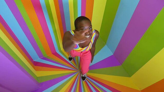 Beautiful young woman dancing and having fun inside a rainbow box room