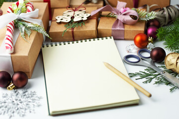 On a light table there is a blurred image of Christmas gifts, a notebook with space for writing text and a pen.
