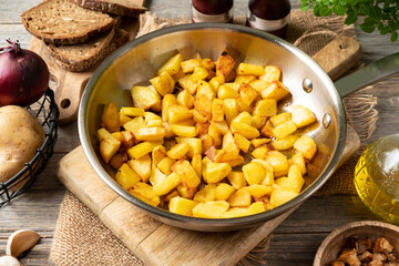 Fried potatoes in a frying pan on a gray wooden table closeup