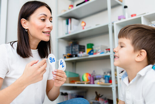 A cute boy with a speech therapist is taught to pronounce the letters, words and sounds.