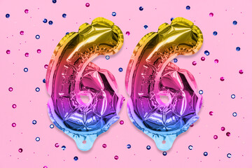 Rainbow foil balloon number, digit sixty six on a pink background with sequins. Birthday greeting card with inscription 66. Anniversary concept. Top view. Numerical digit. Celebration event, template.