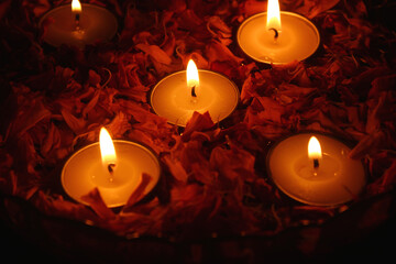 burning tea light candles and marigold flower petals in the dark
