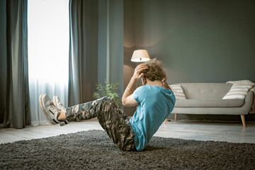 Athletic Man Does Sit-ups on the Carpet in His Apartment. A Strong Man Does Cardio At His Light...