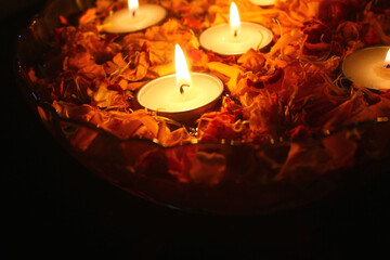 burning tea light candles and marigold flower petals in a bowl filled with water 