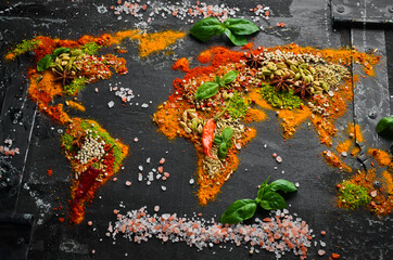 Spice banner. The map of the world is made of various spices and seasonings on a dark background. Top view.