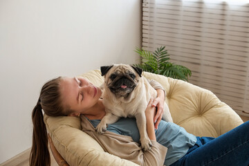 Adorable adult pug in arms of its loving owner. Small adorable doggy with funny wrinkly face with a woman. Close up, copy space, background.