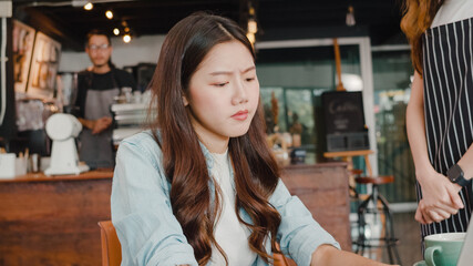 Young Asia freelance lady client talk dispute with millennial waitress feel dissatisfied with cafe bad service, mad disappointed customers speak with staff complain about wrong order coffee shop.