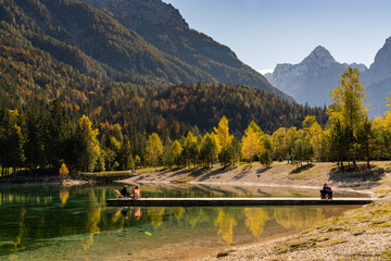 tourists enjoy relaxing on the wooden dock at Lake Jasna in the Slovenian Alps