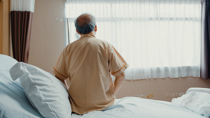 Little girl Asian granddaughter visiting hug sick senior grandfather hospitalized sit on hospital...