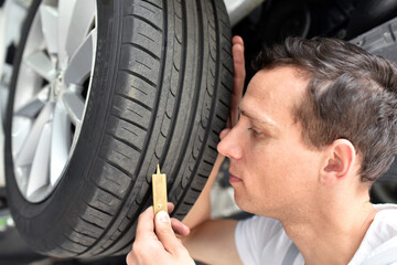 mechanic controls tread depth of a car tyre