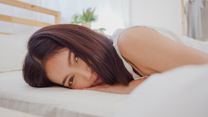 Obraz na płótnie Canvas Asian woman smiling lying on bed in bedroom, Beautiful japanese female using relax time after wake up at home. Lifestyle women using relax time at home concept.
