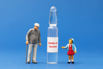 Little toy men made of plastic and an ampoule with a vaccine on a blue background, the concept of...