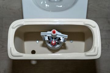 white toilet tank with an open lid and flush system. Plastic toilet drain system.