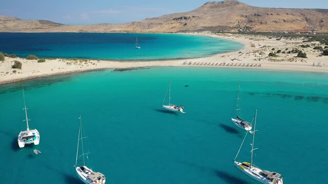 Aerial drone top down video of organised with sun beds and umbrellas paradise sandy beach of Simos with crystal clear turquoise sea, island of Elafonisos, Lakonia, Peloponnese, Greece
