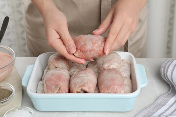 Woman making stuffed cabbage rolls at table, closeup