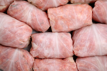 Uncooked stuffed cabbage rolls on plate, top view