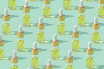 Dropper bottles pattern with cosmetic oil or serum with pipette on mint background copy space