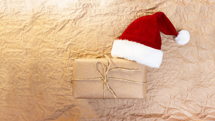 a gift box tied with twine and a Santa Claus hat lie on the crumpled surface of kraft paper. gift wrapping for christmas and new year. Wrapping kraft paper and twine. Ecological packaging. Paper back
