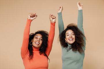 Two happy young curly black women friends 20s wearing casual shirts clothes doing winner gesture...